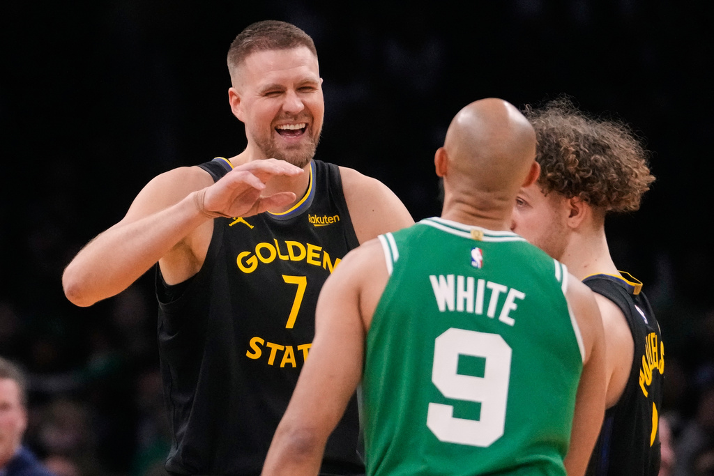 Golden State Warriors center Kristaps Porzingis (7) jokes with his former teammate Boston Celtics guard Derrick White (9) during the first half of an NBA basketball game, Wednesday, March 18, 2026, in Boston. (AP Photo/Charles Krupa)