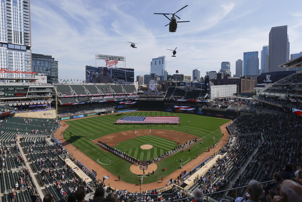 Helicopters pass over Target Field during the national anthem before a baseball game between the Arizona Diamondbacks and the Minnesota Twins, Sunday, Sept. 14, 2025, in Minneapolis. (AP Photo/Bailey Hillesheim)