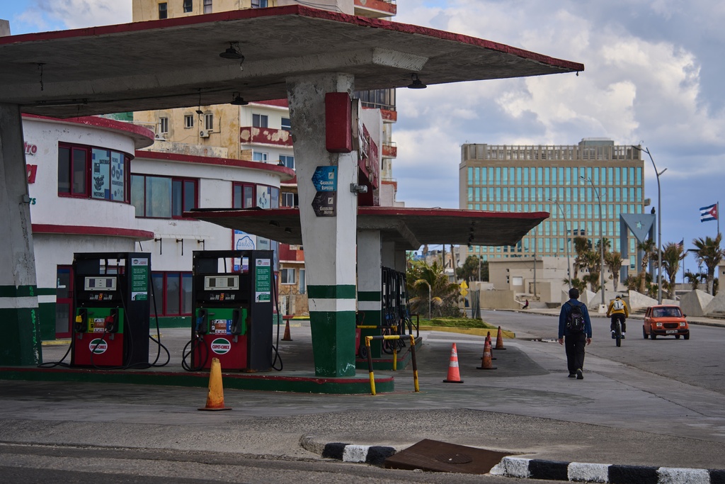 A man walks past a gas station that has run out of fuel, located near the U.S embassy, pictured in the background, in Havana, Cuba, Saturday, Feb. 7, 2026. (AP Photo/Ramon Espinosa)