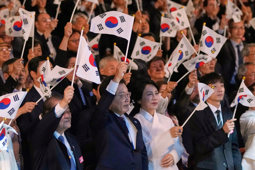 South Korean President Lee Jae Myung, center left, and his wife Kim Hea Kyung, center right, wave the national flags during the 80th anniversary of Korea's liberation from Japanese colonial rule in Seoul, South Korea, Friday, Aug. 15, 2025. (AP Photo/Ahn Young-joon, Pool)