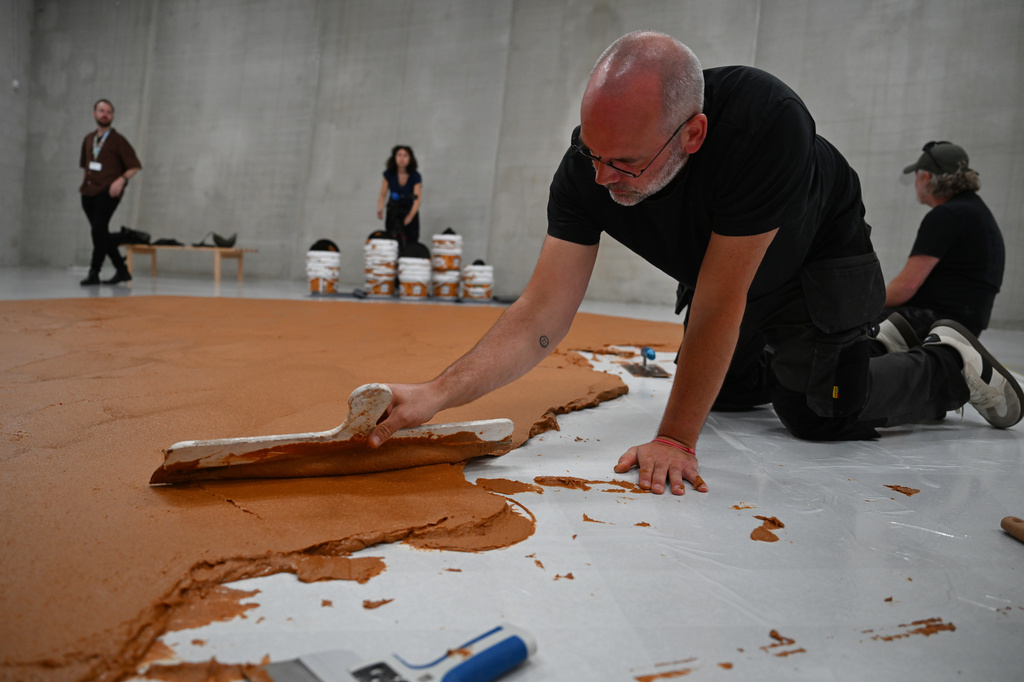 Workers spread peanut butter on a floor to recreate the "Peanut Butter Floor" artwork in tribute to Dutch artist Wim T. Schippers at the Museum Boijmans Van Beuningen in Rotterdam, Netherlands, Friday, July 3, 2026. (AP Photo/Mouneb Taim)