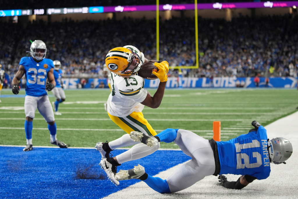 Green Bay Packers wide receiver Dontayvion Wicks (13) makes a catch for a touchdown over Detroit Lions safety Thomas Harper (12) during the first half an NFL football game in Detroit, Thursday, Nov. 27, 2025. (AP Photo/Ryan Sun)