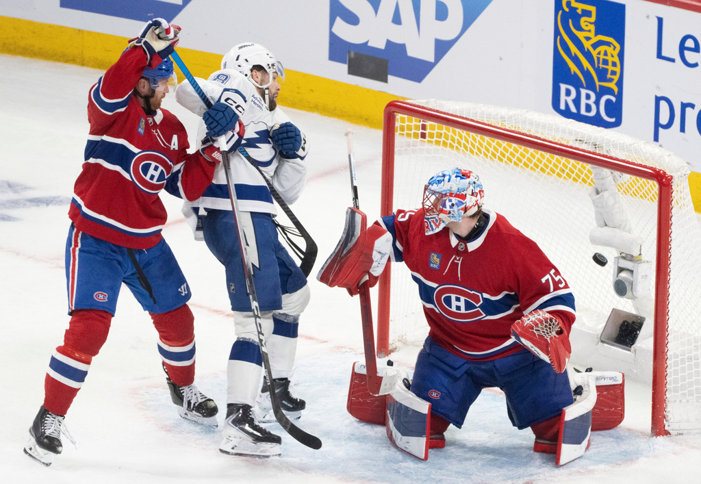 Tampa Bay Lightning's Brandon Hagel (38) scores past Montreal Canadiens goaltender Jakub Dobes (75) and Mike Matheson (8) during the third period of an NHL playoff hockey game, in Montreal, Sunday, April 26, 2026. (Christinne Muschi/The Canadian Press via AP)