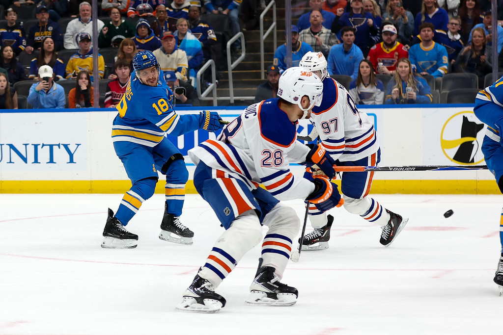 St. Louis Blues' Robert Thomas (18) shoots a goal past Edmonton Oilers' Jack Roslovic (28) and Connor McDavid (97) during overtime period of an NHL hockey game Friday, March 13, 2026, in St. Louis. (AP Photo/Scott Kane)