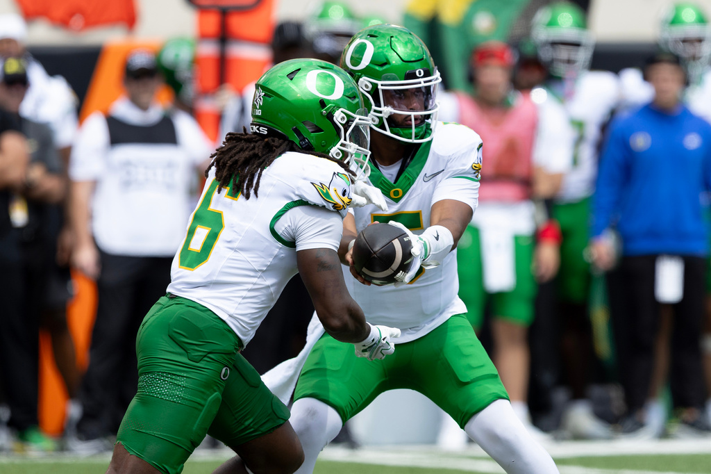 Oregon quarterback Dante Moore (5) hands the ball off to running back Dierre Hill Jr. (6) in the first half of the NCAA college football game against Oklahoma State in Stillwater, Okla., Saturday, Sept. 12, 2026. (AP Photo/Mitch Alcala)