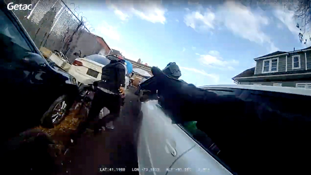 In this photo taken from video released by the Bridgeport Police Department, Bridgeport Police officer Yoon Heo points his gun as Dyshan Best runs while holding a gun Monday, March 31, 2025, in Bridgeport, Conn. (Bridgeport Police Department via AP)