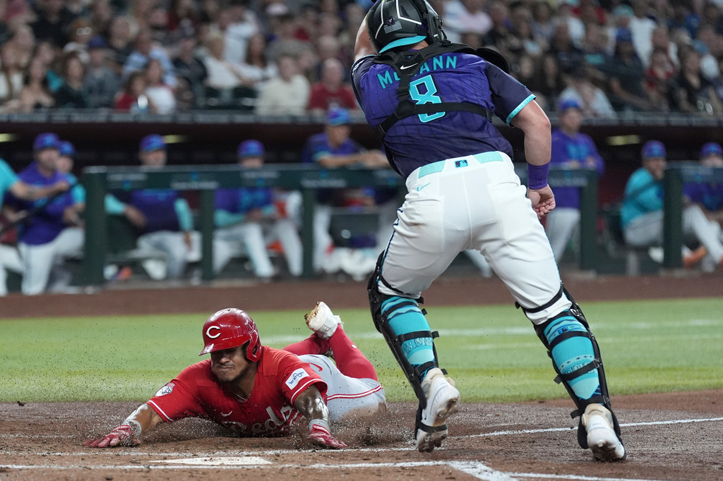 Cincinnati Reds' Dane Myers, left, scores a run as Arizona Diamondbacks catcher James McCann (8) gets a late throw during the third inning of a baseball game, Sunday, Aug. 23, 2026, in Phoenix. (AP Photo/Ross D. Franklin)