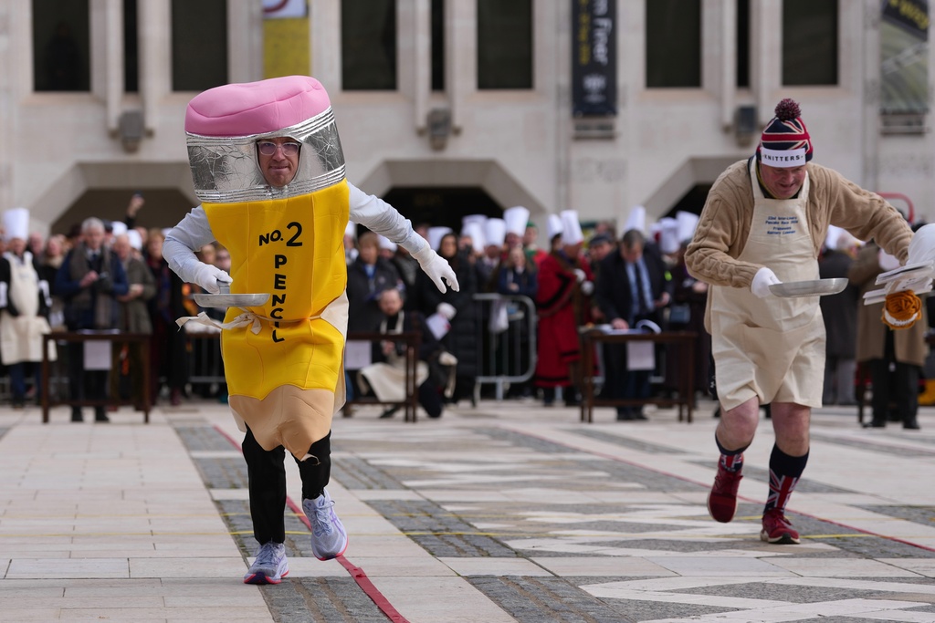 Competitors participate in a traditional pancake race by livery companies at the Guildhall in London, Tuesday, Feb. 17, 2026. (AP Photo/Kin Cheung)