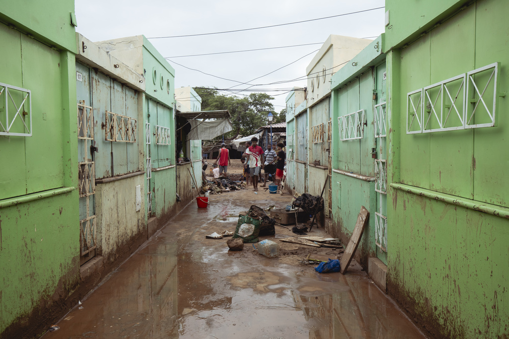 People clear debris from an alley between closed shops after flooding in São Vicente, Cabo Verde, Thursday, Aug 14, 2025. (AP Photo/Queila Fernandes)