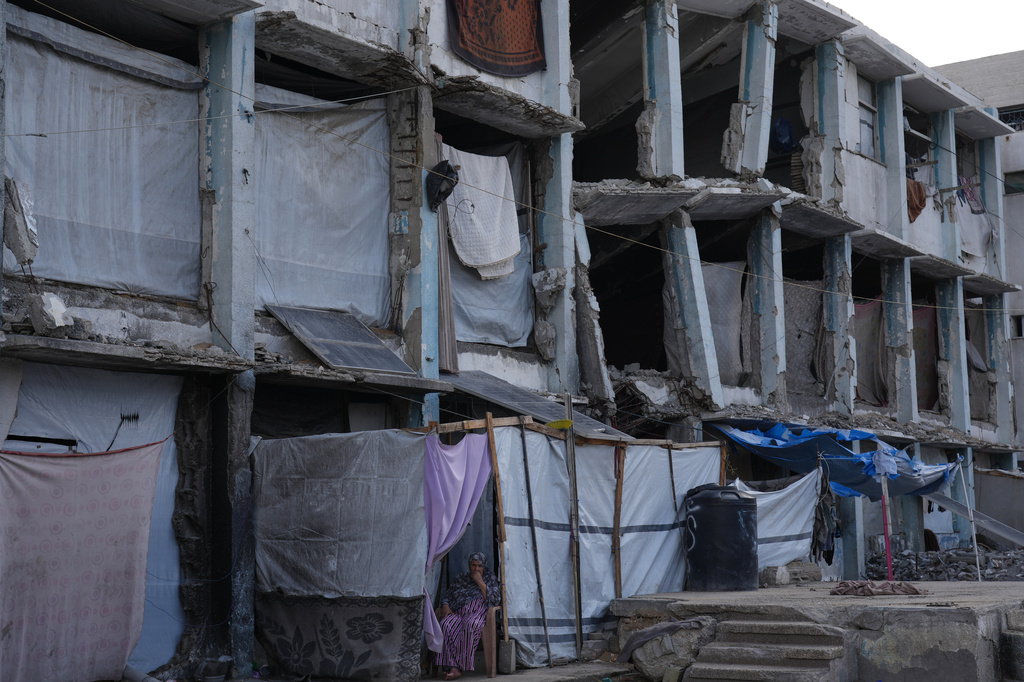 A displaced Palestinian woman sits at the entrance of her tent adjacent to a destroyed U.N.-run school on the first day of the new academic year, in the Shati refugee camp in Gaza City, Saturday, Sept. 19, 2026. (AP Photo/Jehad Alshrafi)