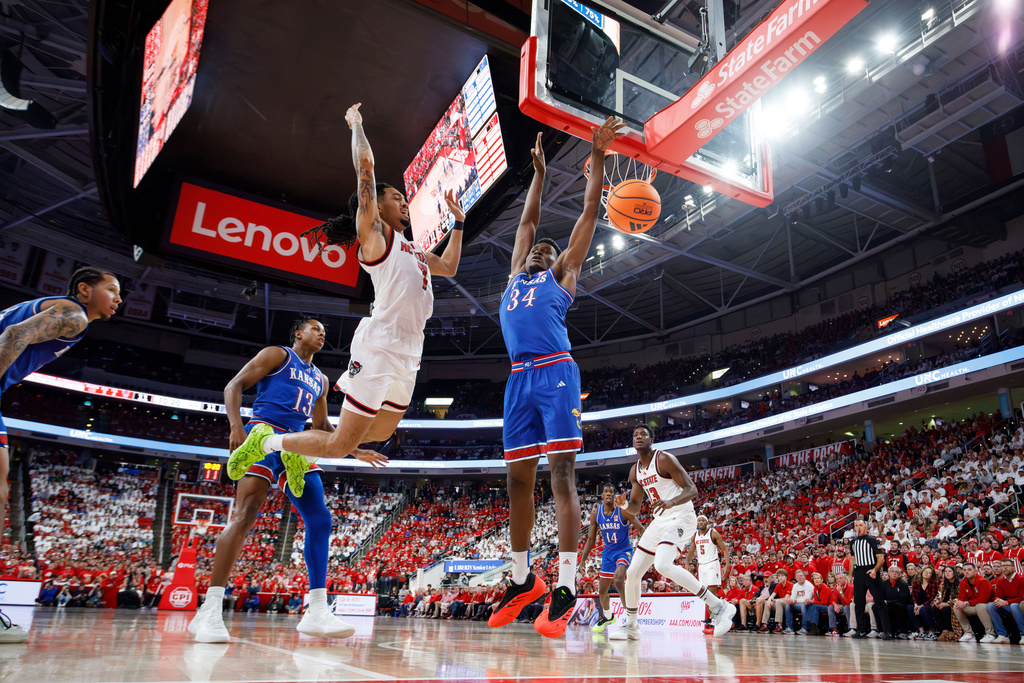 North Carolina State's Alyn Breed (7) loses the ball as Kansas's Paul Mbiya (34) and Elmarko Jackson (13) defend during the first half of an NCAA college basketball game in Raleigh, N.C., Saturday, Dec. 13, 2025. (AP Photo/Ben McKeown)