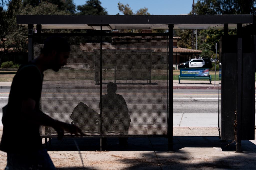 A person sits in the shade at a bus stop in Los Angeles, Friday, July 31, 2026. (AP Photo/Jae C. Hong)
