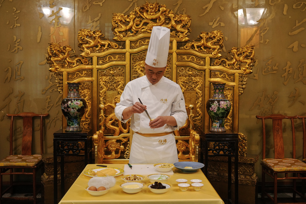 Chef Fan Liangliang demonstrates making a dish at Fangshan Restaurant inside Beihai Park in Beijing on July 23, 2026. (AP Photo/Andy Wong)