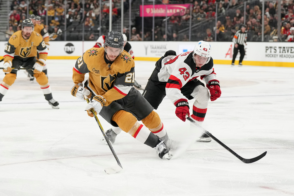 Vegas Golden Knights center Brett Howden (21) skates with the puck against New Jersey Devils defenseman Luke Hughes (43) during the second period of an NHL hockey game Wednesday, Dec. 17, 2025, in Las Vegas. (AP Photo/Candice Ward)