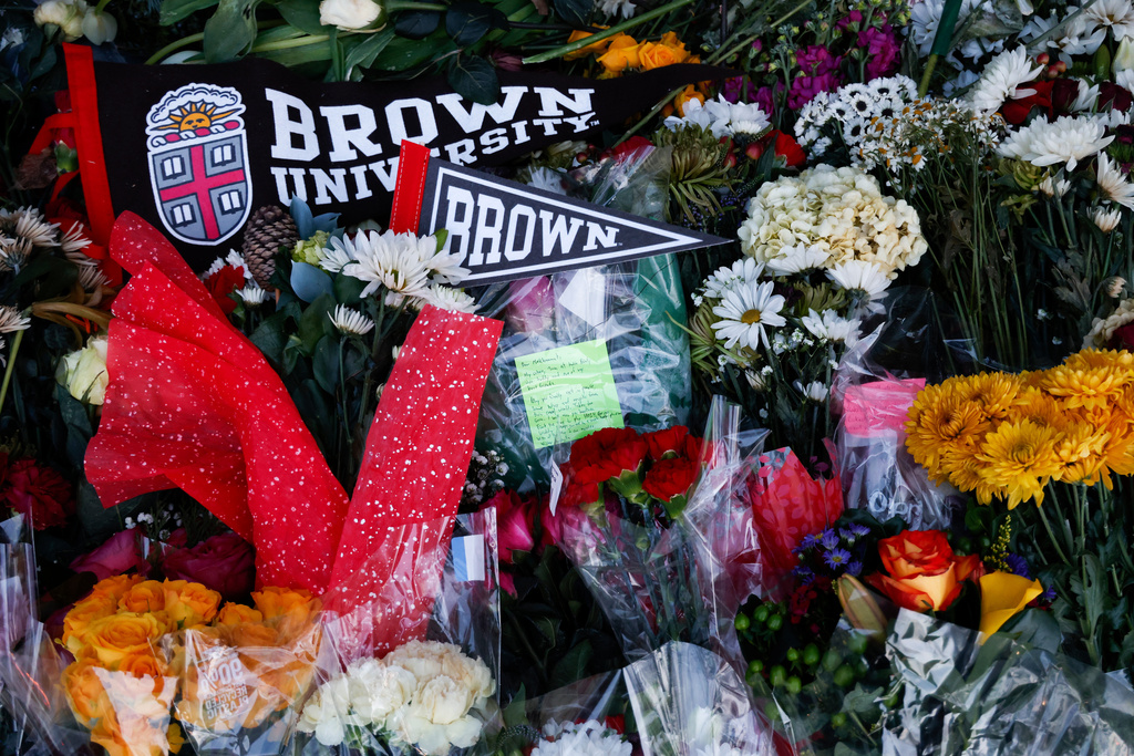 Community flowers, notes and mementos are placed in a makeshift memorial display in front of Brown University's Van Wickle gates, in Providence, R.I., two days after a shooting took place on Brown University's campus, Monday, Dec. 15, 2025. (Lily Speredelozzi/The Sun Chronicle via AP)