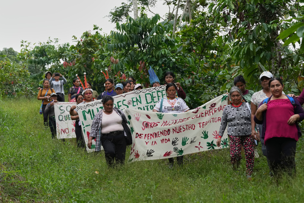 A group of Indigenous women from across Ecuador's Amazon carry signs as they travel through the region on what they call call a toxitour, visiting oil fields in Sucumbios, Ecuador, Friday, March 6, 2026. (AP Photo/Dolores Ochoa)