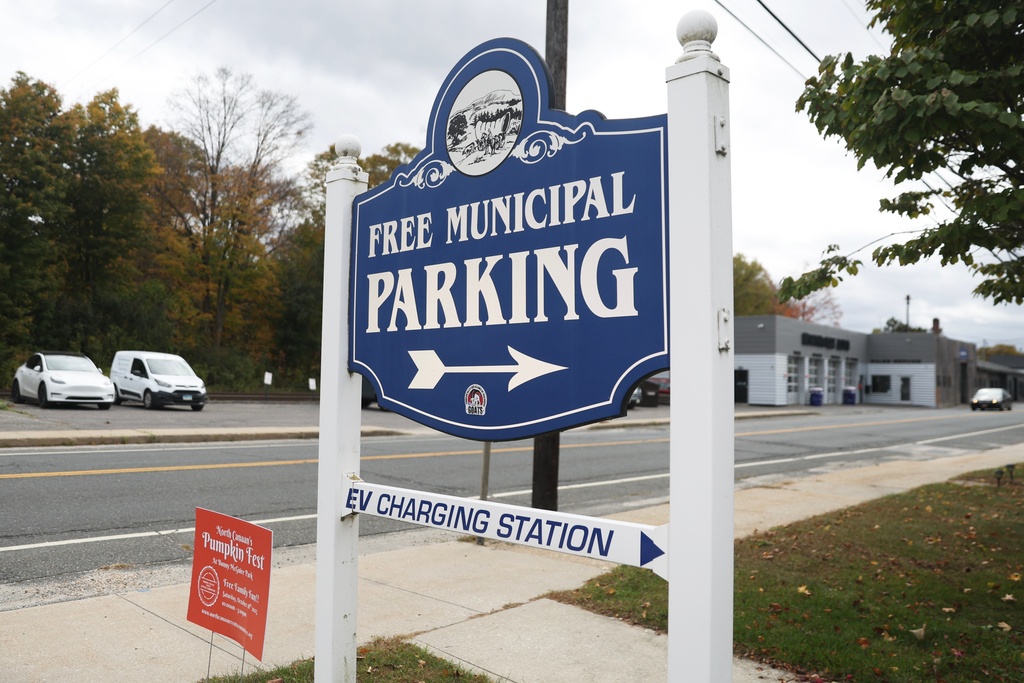 A sign points to a municipal lot with a Level 2 EV charger Saturday, Oct. 11, 2025, in North Canaan, Conn. (AP Photo/Heather Khalifa)