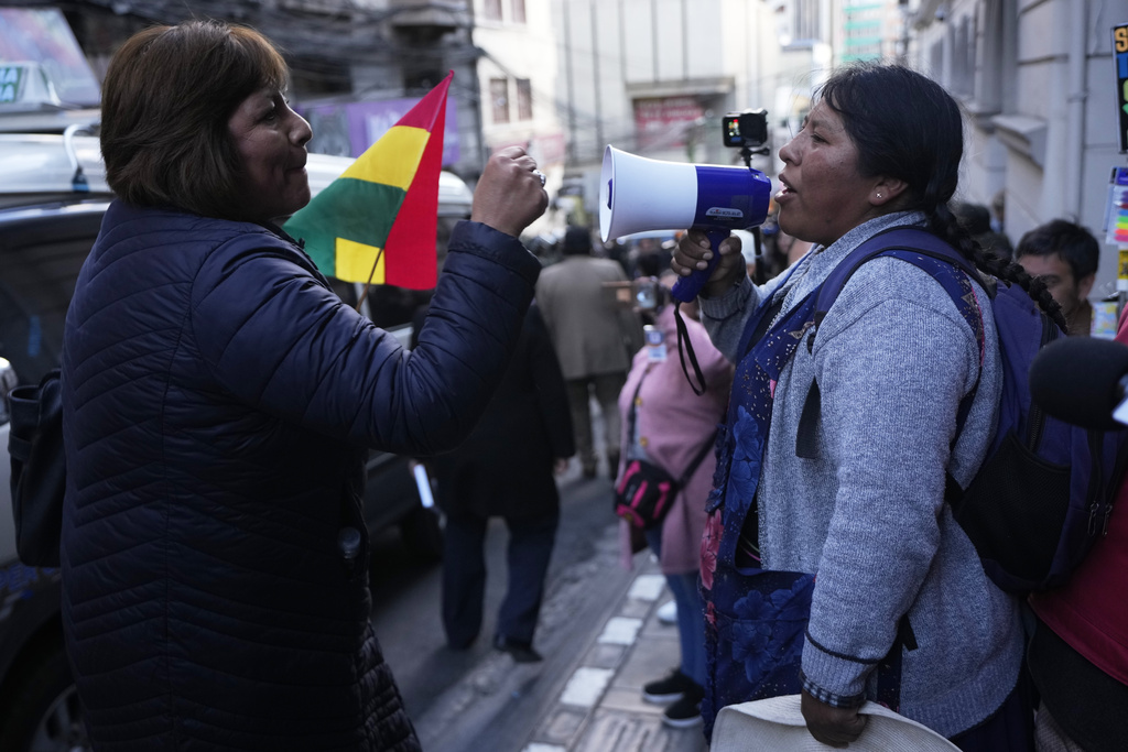 A supporter of suspended Santa Cruz Governor Luis Fernando Camacho blocks an anti-Camacho demonstrator, right, during a court hearing regarding the length of Camacho's pretrial detention stemming from the crisis over the 2019 ouster of former President Evo Morales, in La Paz, Bolivia, Tuesday, Aug. 26, 2025. (AP Photo/Juan Karita)