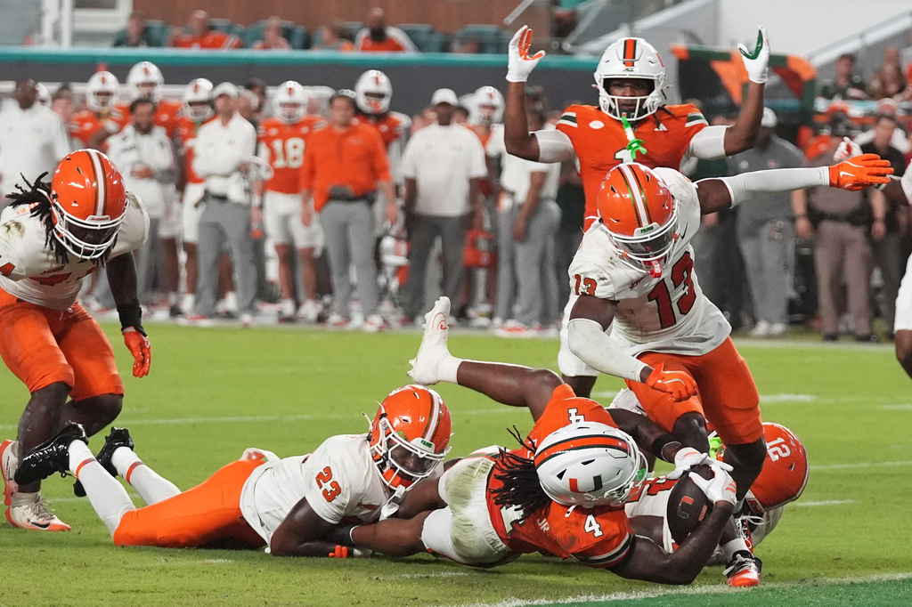Miami running back Mark Fletcher Jr. (4) is stopped at the goal line as Florida A&M defensive back Dion Villiers (23) and defensive back Justin Bostic (13) defend during the first half of an NCAA college football game, Thursday, Sept. 10, 2026, in Miami Gardens, Fla. (AP Photo/Lynne Sladky)