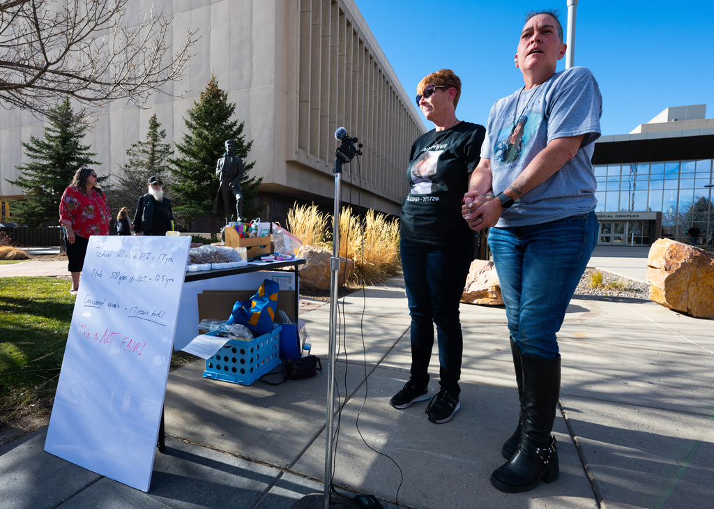 Crystina Page, right, hold the hand of Heather DeWolf as they speak to the press outside the El Paso County Courthouse, in Colorado Springs, Colo., Monday, Dec. 22, 2025, before a court hearing for Return to Nature funeral home owners Jon and Carie Hallford. (Christian Murdock/The Gazette via AP)