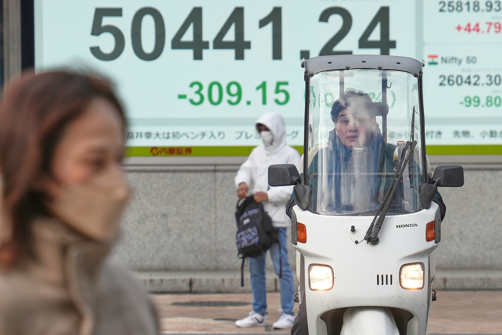 A person rides a motorcycle in front of an electronic stock board showing Japan's Nikkei index at a securities firm, Monday, Dec. 29, 2025, in Tokyo. (AP Photo/Eugene Hoshiko)