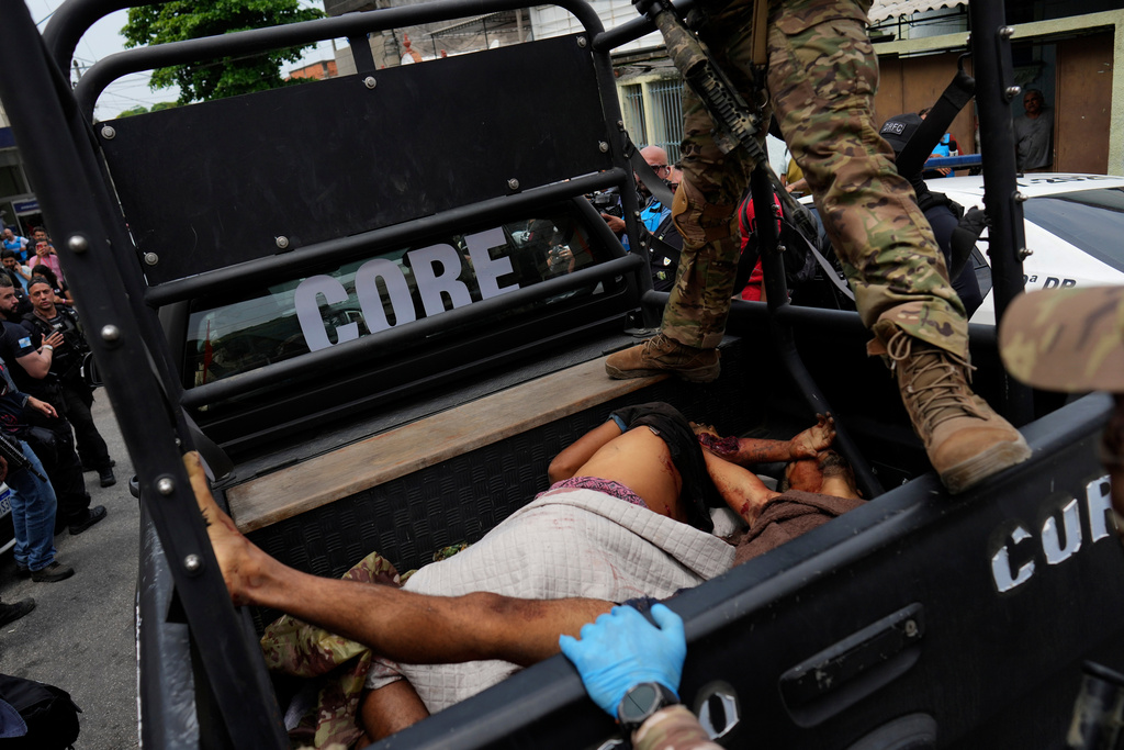 EDS NOTE: GRAPHIC CONTENT - A police officer stands over bloodied people lying in the back of a police truck brought to the Getulio Vargas Hospital during a police operation against alleged drug traffickers in the Complexo do Alemao favela where the criminal organization "Comando Vermelho" operates in Rio de Janeiro, Tuesday, Oct. 28, 2025. (AP Photo/Silvia Izquierdo) EDS NOTE: GRAPHIC CONTENT - A police officer stands over bloodied people lying in the back of a police truck brought to the Getulio Vargas Hospital during a police operation against alleged drug traffickers in the Complexo do Alemao favela where the criminal organization "Comando Vermelho" operates in Rio de Janeiro, Tuesday, Oct. 28, 2025. (AP Photo/Silvia Izquierdo)