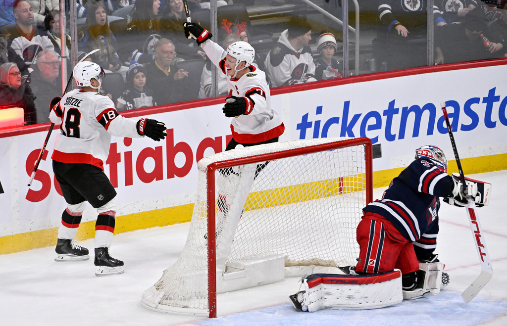 Ottawa Senators' Brady Tkachuk (7) celebrates after his winning goal in overtime against Winnipeg Jets' goaltender Connor Hellebuyck, right, with Tim Stulzle (18) during an NHL hockey game in Winnipeg, Manitoba, Monday, Dec. 15, 2025. (Fred Greenslade/The Canadian Press via AP)
