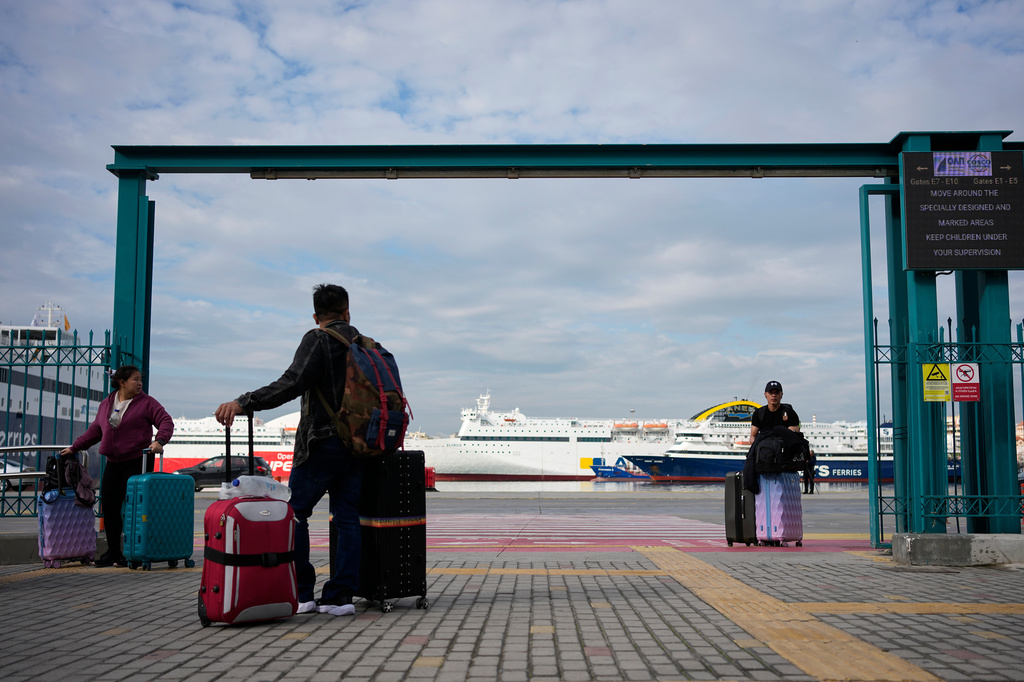 Passengers walk through the port of Piraeus during a 24-hour seafarers' strike over pay, working conditions and safety, alongside protests by port workers against the transport of military equipment through ports, near Athens, Greece, Friday, Oct. 30, 2026. (AP Photo/Thanassis Stavrakis)