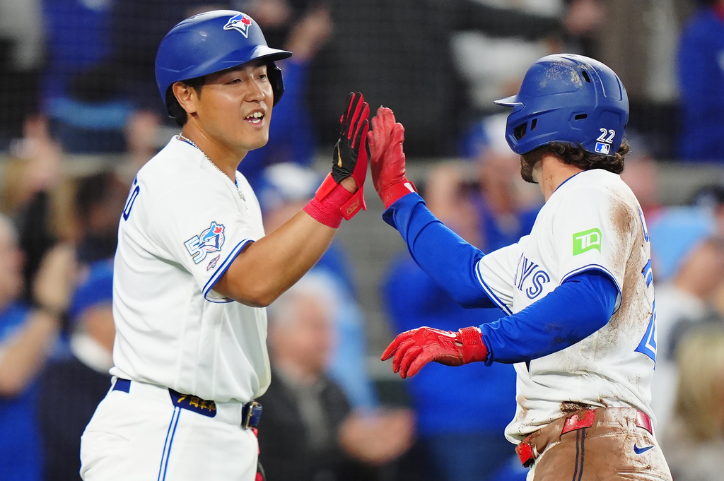Toronto Blue Jays' Kazuma Okamoto (left) and Ernie Clement (22) celebrate after they both scored during the fifth inning of a baseball game against the Athletics in Toronto on Friday, March 27, 2026. (Frank Gunn/The Canadian Press via AP)