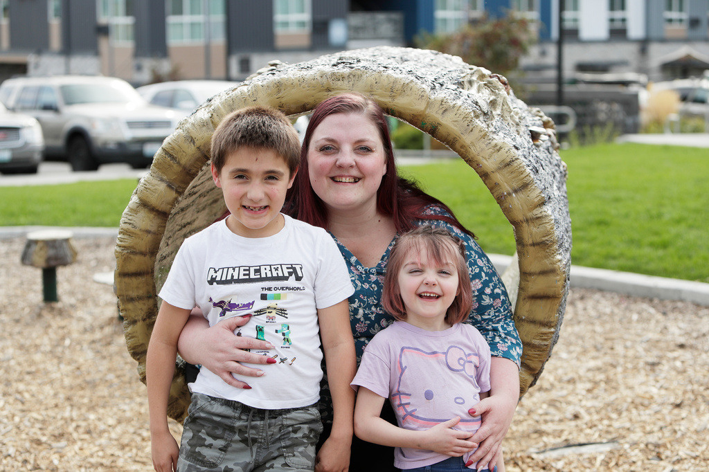 Cassie Reed, center, sits for a photograph with her son Kian Reed, left, and daughter Evie Reed outside their apartment building, Tuesday, Sept. 22, 2026, in Spokane, Wash. (AP Photo/Young Kwak)