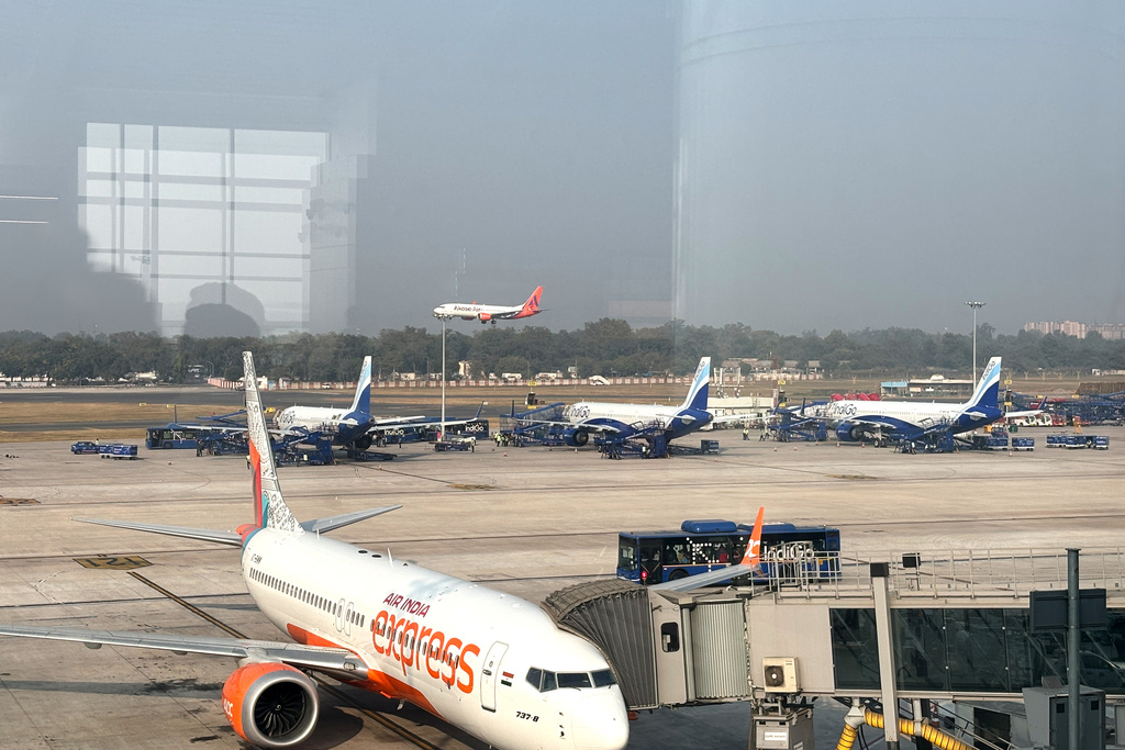 Three Indigo Airlines planes are seen through a glass window at the Indira Gandhi International Airport in New Delhi as several flights operated by the carrier were either cancelled or delayed, India, Thursday, Dec. 4, 2025. (AP Photo/Manish Swarup)