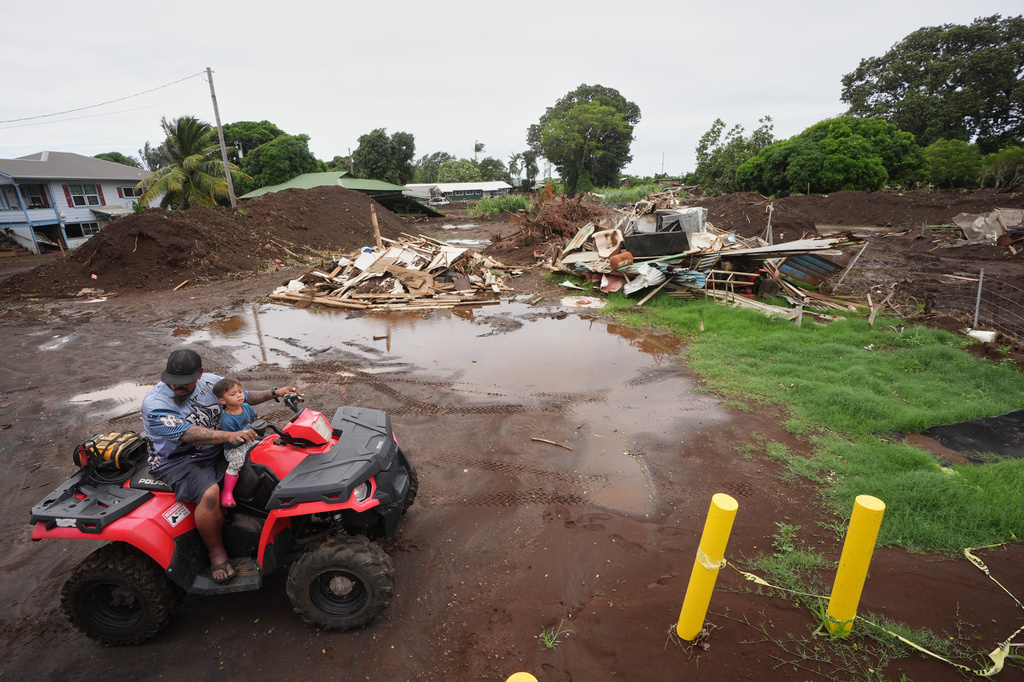 A man rides with his son near where a home was destroyed during last month's Hurricane Lala, as floodwaters from Hurricane Nolo recedes Sunday, Sept. 27, 2026, in Naalehu, Hawaii. (AP Photo/Gregory Bull)