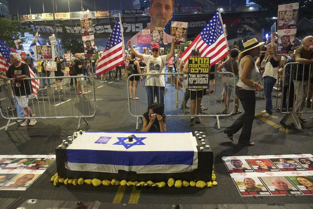 Einav Zangauker, center, mother of Matan Zangauker who is held hostage by Hamas, sits beside an installation resembling a coffin during a protest demanding an end to the war and the immediate release of hostages held by Hamas in the Gaza Strip, in Tel Aviv, Israel, Tuesday, Aug. 12, 2025. (AP Photo/Ariel Schalit)