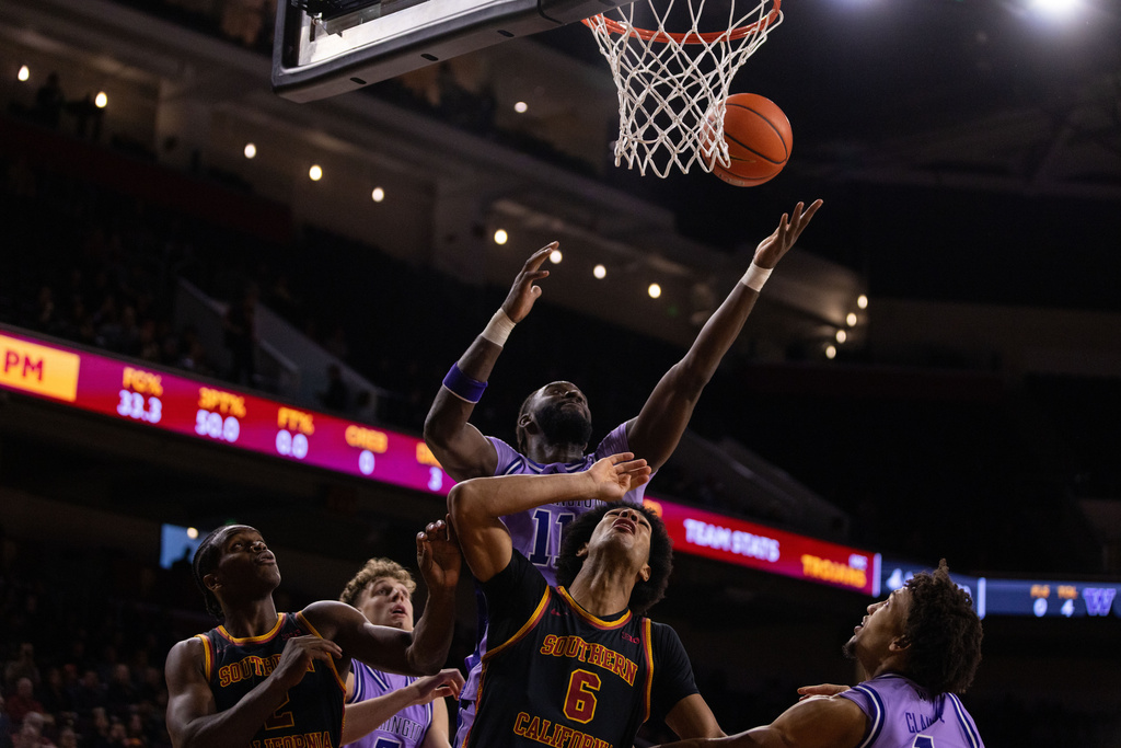 Southern California forward Jacob Cofie (6) and Washington center Franck Kepnang (11) fight for the ball during the first half of an NCAA college basketball game Saturday, Dec. 6, 2025, in Los Angeles. (AP Photo/Ethan Swope)