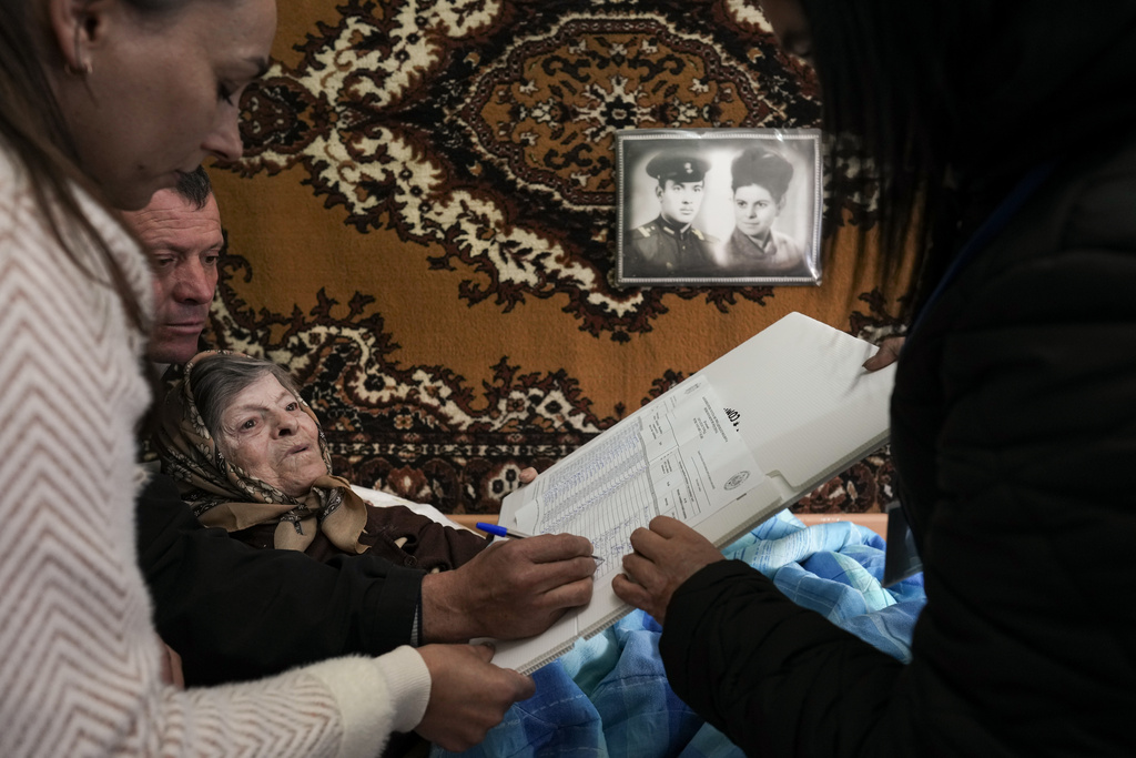 FILE - Tatiana, 78 years old, signs her name to receive a stamp to cast her vote in a mobile ballot box in the village of Hrusevo, Moldova, Sunday, Oct. 20, 2024. (AP Photo/Vadim Ghirda, File)