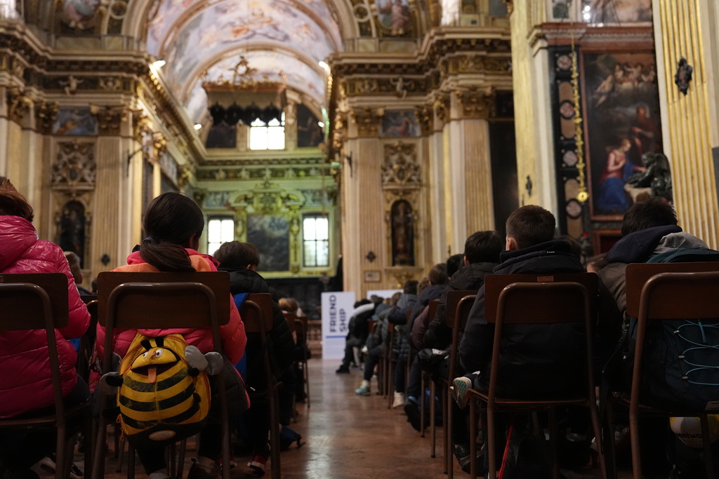 Children sit inside the Church of Sant’Antonio during an activity linked to the “Tour of Sports Values,” an initiative connected to the 2026 Winter Olympics, in Milan, Italy, Monday, Feb. 9, 2026. (AP Photo/María Teresa Hernandez)
