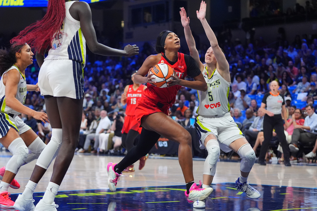 Atlanta Dream forward Angel Reese, center, drives against Dallas Wings guard Paige Bueckers (5) during the second half of a WNBA basketball game in Arlington, Texas, Wednesday, July 29, 2026. (AP Photo/LM Otero)