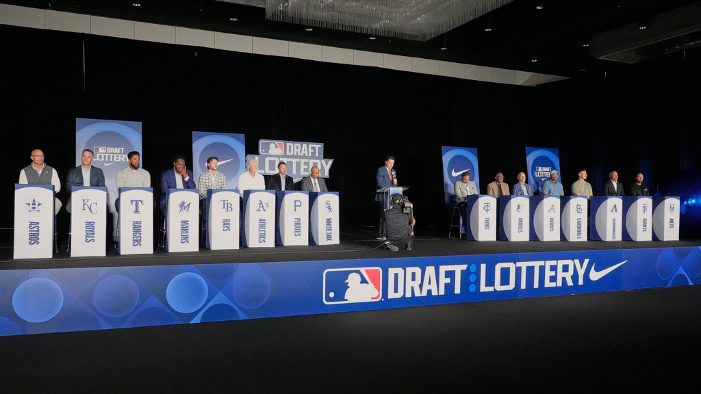 Representatives from 15 Major League Baseball teams wait for the lottery draft order to be announced during a live broadcast at the baseball winter meetings, Tuesday, Dec. 9, 2025, in Orlando, Fla. (AP Photo/John Raoux)