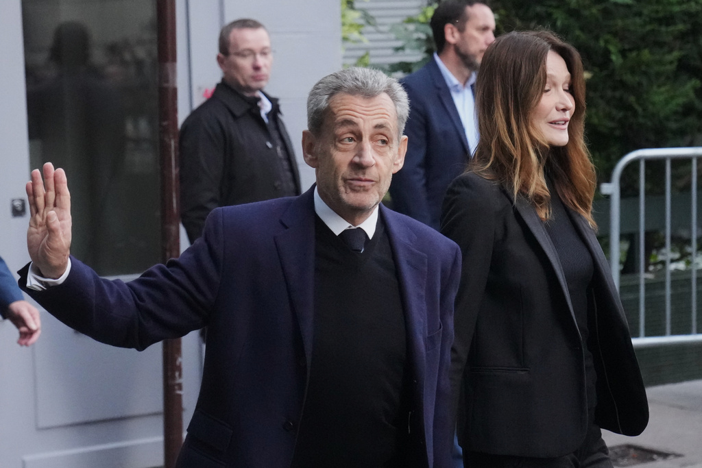 Former French President Nicolas Sarkozy and his wife Carla Bruni-Sarkozy leave their home Tuesday, Oct. 21, 2025 in Paris as Nicolas Sarkozy heads to prison to serve time for a criminal conspiracy to finance his 2007 election campaign with funds from Libya. (AP Photo/Thibault Camus)