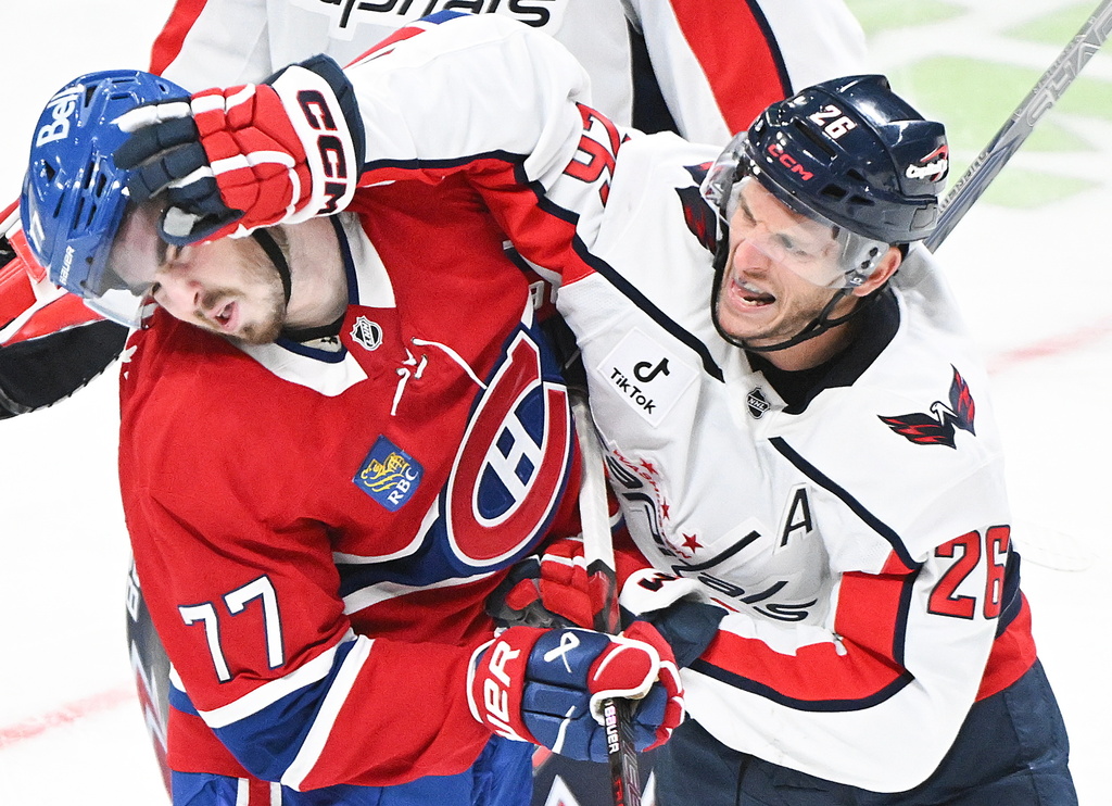 Washington Capitals' Nic Dowd (26) tries to face wash Montreal Canadiens' Kirby Dach (77) during the third period of an NHL hockey game in Montreal, Saturday, Feb. 28, 2026. (Graham Hughes/The Canadian Press via AP)