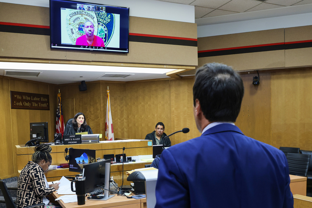 Former NFL star wide receiver Antonio Brown, on monitor above, appears for his bond hearing via video after his attorney Mark Eiglarsh, right, filed a written plea of "not guilty" for an attempted murder charge as Judge Mindy S. Glazer presides, Wednesday, Nov. 12, 2025, in Miami. (Carl Juste/Miami Herald via AP, Pool)