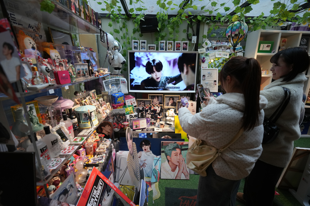 Fans of K-pop band BTS stand look at photos of BTS members at a cafe in Seoul, South Korea, Tuesday, March 17, 2026. (AP Photo/Lee Jin-man)