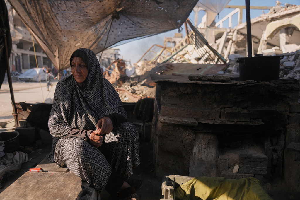 Amal Matar, 65, sits next to the oven as she cooks for her family in the Al-Shati camp, northern Gaza Strip, Thursday, Dec. 25, 2025. (AP Photo/Jehad Alshrafi)