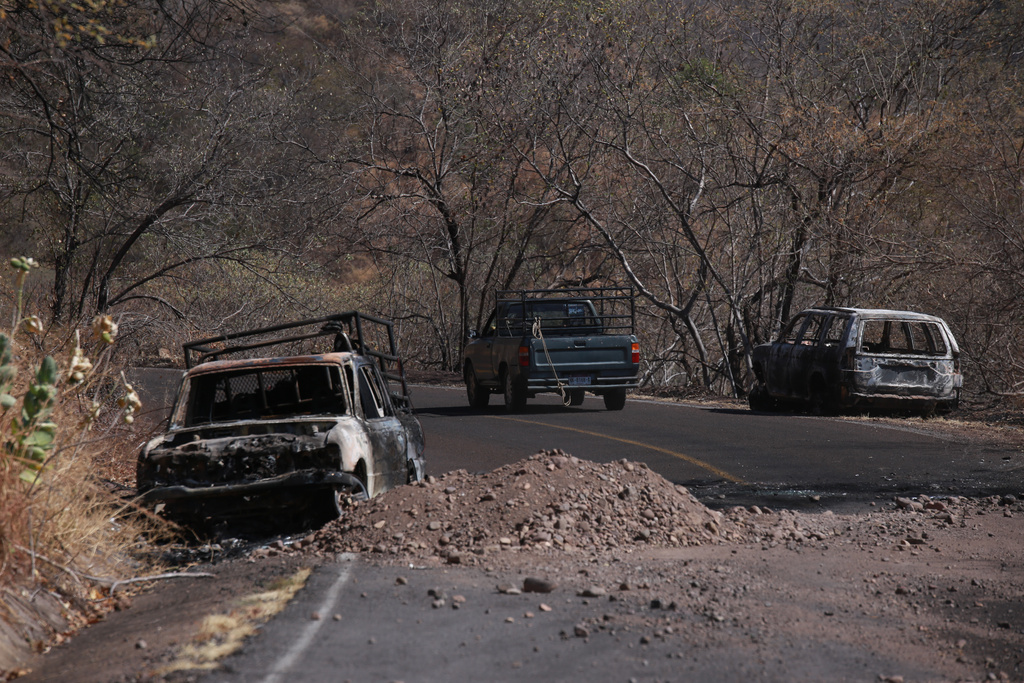 Charred vehicles sit on the side of a highway in Aguililla, Mexico, Tuesday, Feb. 24, 2026, after the Mexican army killed the leader of the Jalisco New Generation Cartel, Nemesio Oseguera Cervantes, known as "El Mencho." (AP Photo/Armando Solis)
