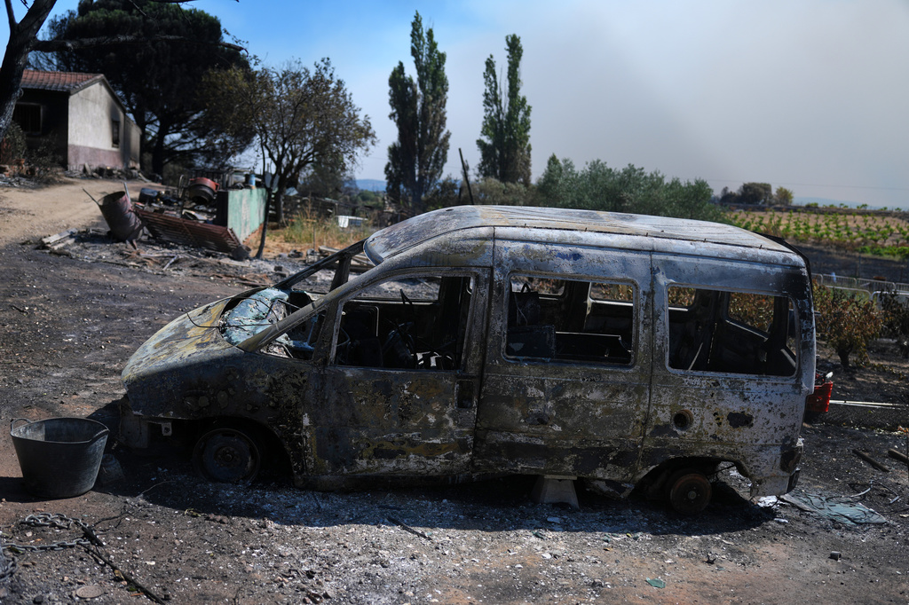 A burnt vehicle sits outside a charred house in Navas del Rey, west of Madrid, Spain, where wildfires have forced tens of thousands to be evacuated, Sunday, July 26, 2026. (AP Photo/Manu Fernandez)