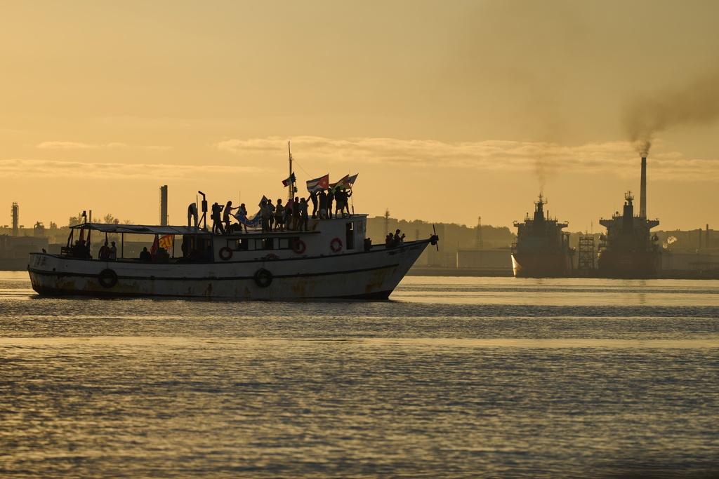 Activists wave Cuban and Palestinian flags from the vessel Maguro, arriving from Mexico with humanitarian aid as part of the "Nuestra America," or Our America convoy, in Havana Bay, Cuba, Tuesday, March 24, 2026. (AP Photo/Ramon Espinosa)