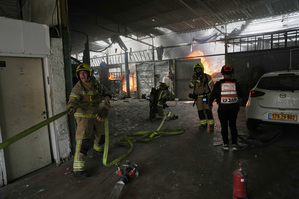 Firefighters try to extinguish a fire at a damaged workshop struck by an Iranian missile in Petah Tikva, Israel, Tuesday, March 31, 2026. (AP Photo/Oded Balilty)