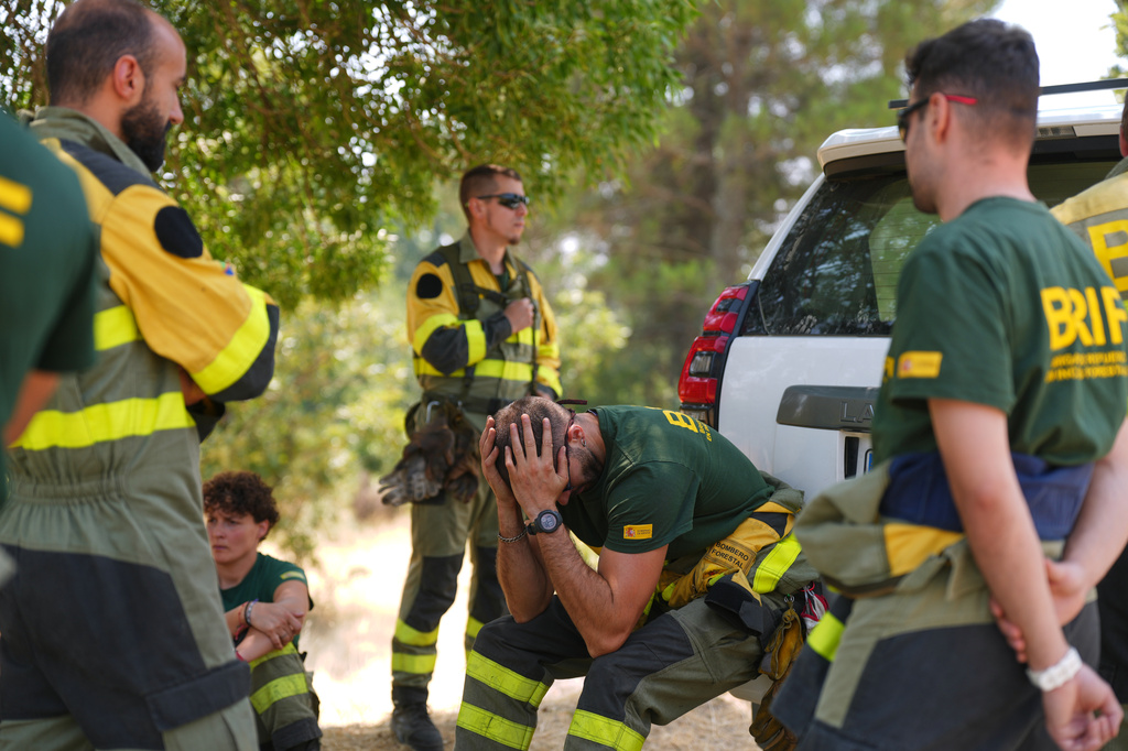 Aesir Diaz, 31, a technician with Spain's Forest Fire Reinforcement Brigades (BRIF), center, sits next to teammates during a break from battling a wildfire in Sotillo de Adrada, Ávila province, Spain, as the fire continues to spread, Tuesday, July 28, 2026. (AP Photo/Manu Fernandez)