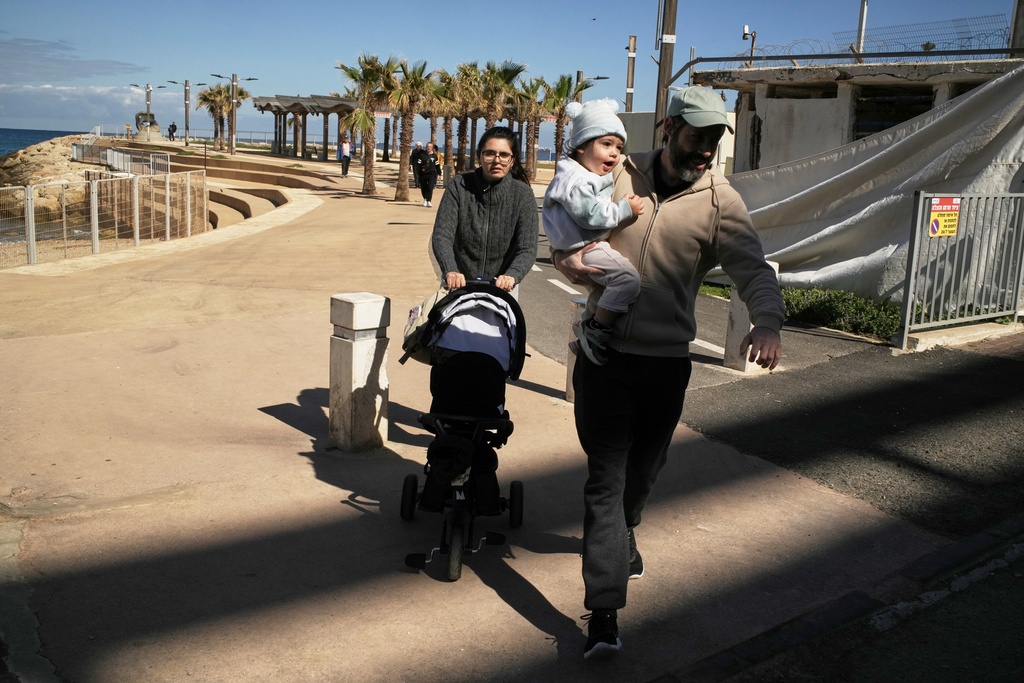 A couple with their two children rush to a shelter after a warning siren sounds following Israeli strikes in Iran, in Haifa, northern Israel, Saturday, Feb. 28, 2026. (AP Photo/Leo Correa)