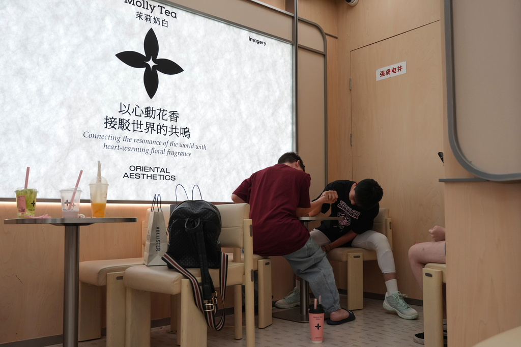 A Chinese teenager arm wrestles with a foreigner at a Molly Tea shop in Beijing, China, Tuesday, July 7, 2026. (AP Photo/Ng Han Guan)